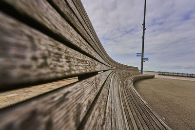 Close-up of wooden bench structure against sky