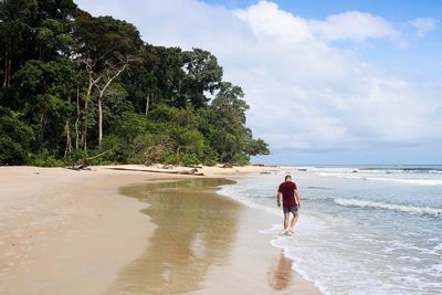 Rear view of woman on beach against sky