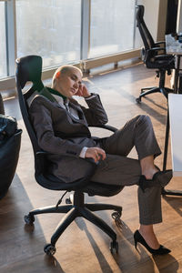 Side view of woman sitting on chair at home