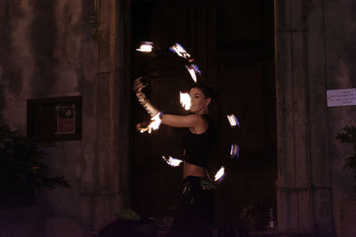 Woman standing by illuminated light on wall at night