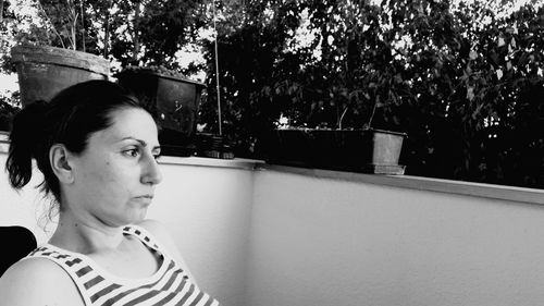 Thoughtful woman resting in balcony against trees