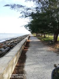 Empty road by sea against sky