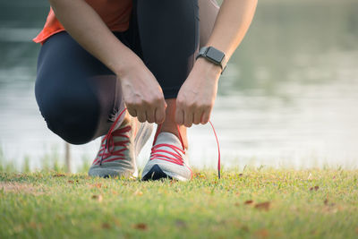 Low section of woman wearing shoes on grass