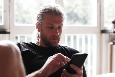 Close-up of man using mobile phone at home