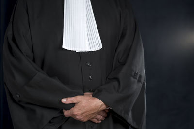 Midsection of lawyer standing against black background