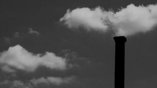 Low angle view of smoke emitting from chimney against sky