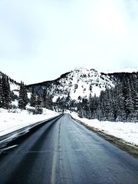 Road amidst snowcapped mountains against sky