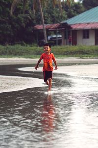 Full length of playful boy running in water