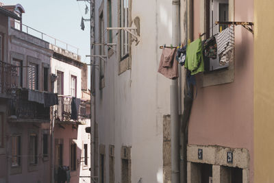 Low angle view of clothes drying on alley amidst buildings. lisbon.