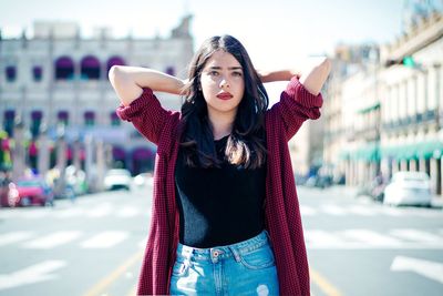 Portrait of young woman standing on street in city