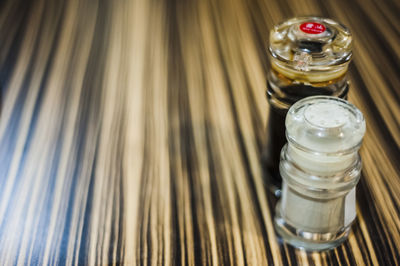 High angle view of soy sauce with pepper shaker on table