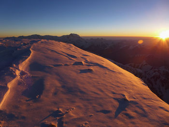 Scenic view of snowcapped mountains against clear sky during sunset