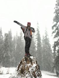 A man dabing standing on a rock while snowfall