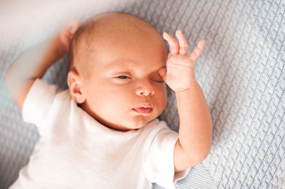 Cute baby boy lying on bed at home