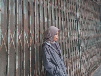 Portrait of woman standing by fence