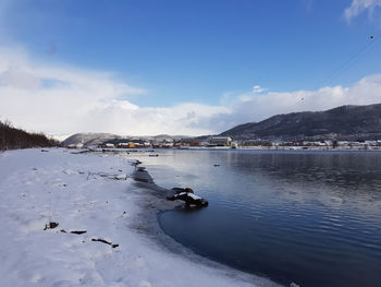 Scenic view of lake by snowcapped mountain against sky