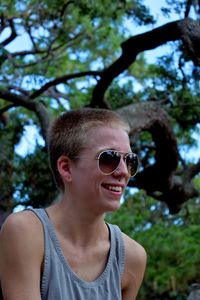 Happy female hipster looking away while sitting in forest