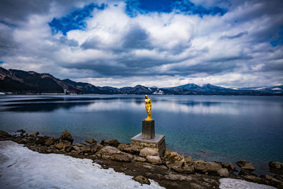 Scenic view of lake by snowcapped mountains against sky