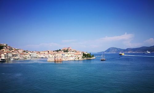 Scenic view of sea by buildings against blue sky