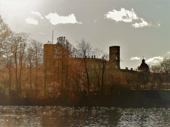 Buildings by river against sky