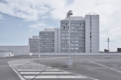 Empty road by buildings against sky in city