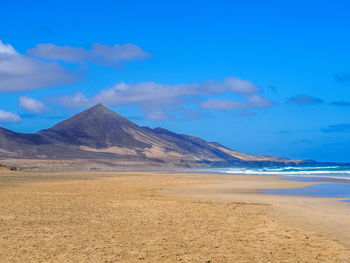 Scenic view of sea and mountains against blue sky