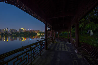 Covered empty walkway by lake with reflection at dusk