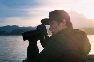 Man photographing with camera against sky