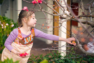 Girl plucking flower at backyard