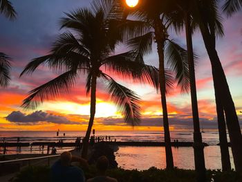 Silhouette palm trees at beach during sunset