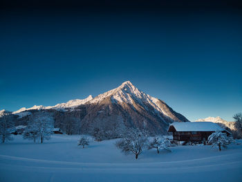 Scenic view of snowcapped mountains against clear blue sky