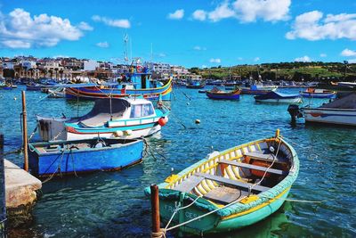 Sailboats moored in sea against sky in city