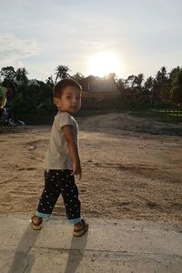 Cute girl standing on field against sky