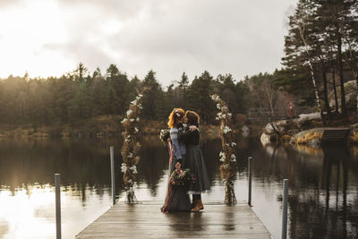 Rear view of women standing on lake during rainy season