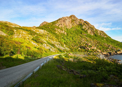 Road amidst green landscape against sky