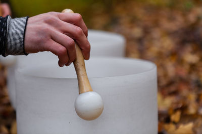 Cropped hands of man playing singing bowl outdoors