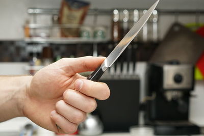 Cropped hand of man holding knife in kitchen