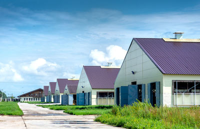 Houses by buildings against blue sky