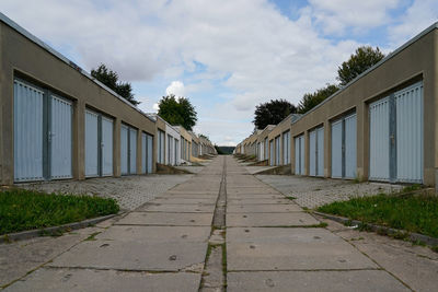 Empty footpath amidst buildings against sky