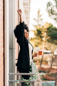 Young woman drinking glass while standing outdoors