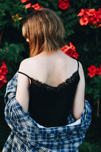 Rear view of woman standing by red flowering plants