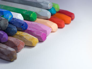 High angle view of multi colored pastel crayons on gray background