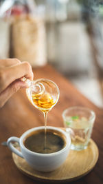 Cropped hand pouring honey in coffee