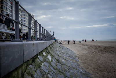 People on beach against cloudy sky