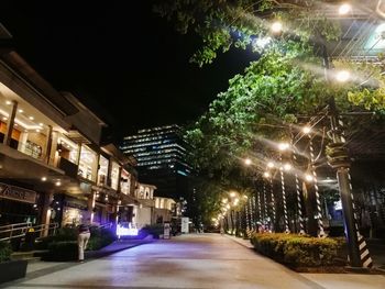 Illuminated street amidst buildings in city at night