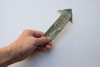 Cropped hand of person holding key against white background