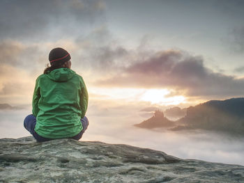 Alone travel woman hiker sits on the edge up midty valley. traveling active lifestyle concept