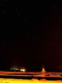 Woman standing on illuminated star field against sky at night