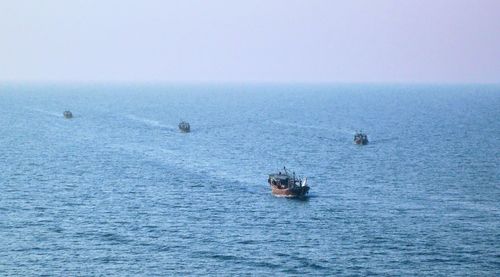 Boats sailing in sea against sky