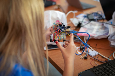 Close-up of woman repairing computer part at table